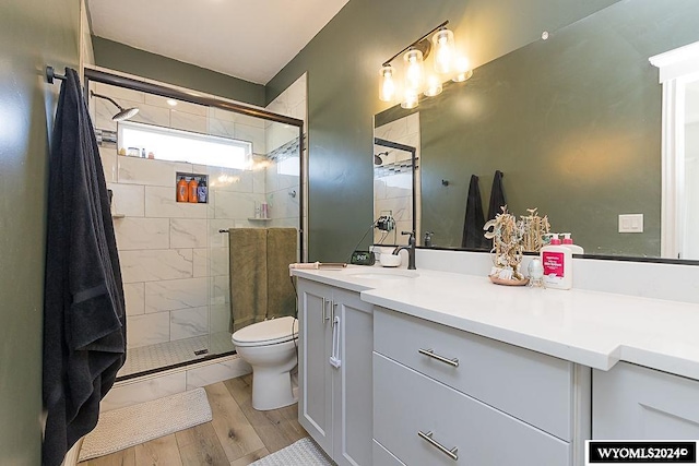 bathroom with vanity, toilet, an enclosed shower, and hardwood / wood-style floors