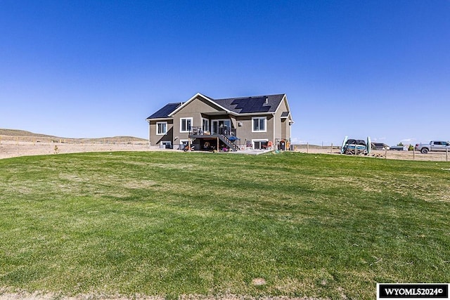 back of property featuring a wooden deck and a lawn