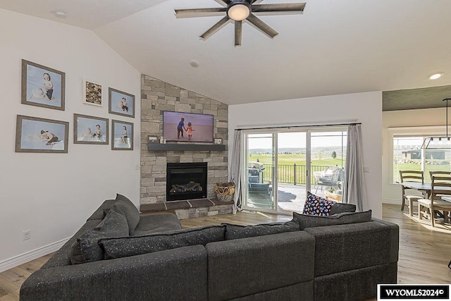 living room featuring lofted ceiling, wood-type flooring, a fireplace, and ceiling fan