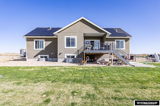 rear view of property featuring a yard and solar panels