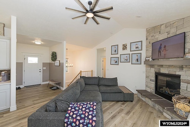 living room with light hardwood / wood-style floors, ceiling fan, a fireplace, and vaulted ceiling