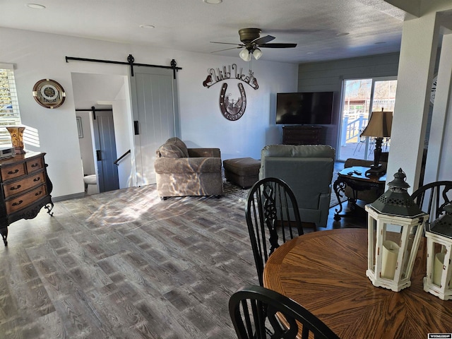 living room featuring a textured ceiling, wood-type flooring, a barn door, and ceiling fan