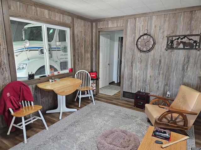 dining space with dark hardwood / wood-style floors and wooden walls