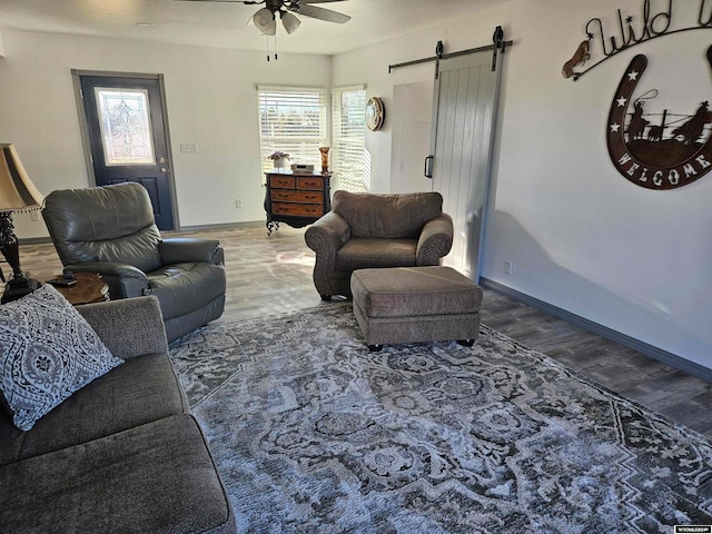 living room featuring a barn door, ceiling fan, and dark wood-type flooring