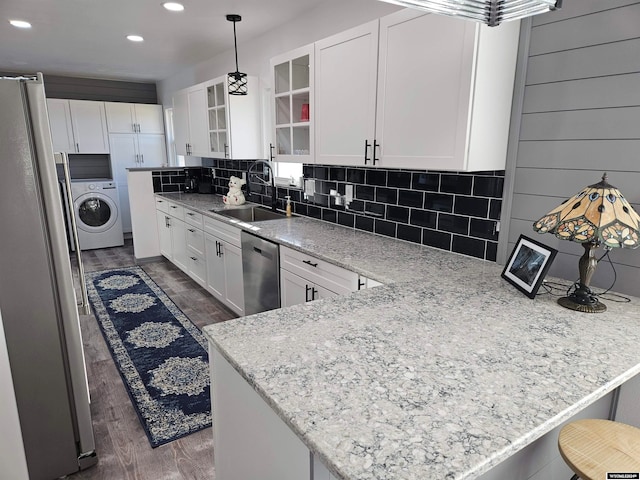 kitchen with dark wood-type flooring, white cabinets, sink, appliances with stainless steel finishes, and washer / clothes dryer