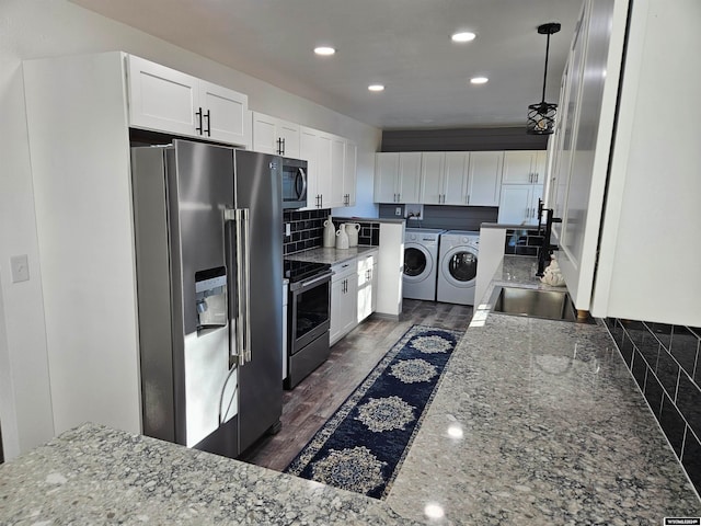 kitchen featuring appliances with stainless steel finishes, dark hardwood / wood-style floors, pendant lighting, white cabinets, and washer and dryer