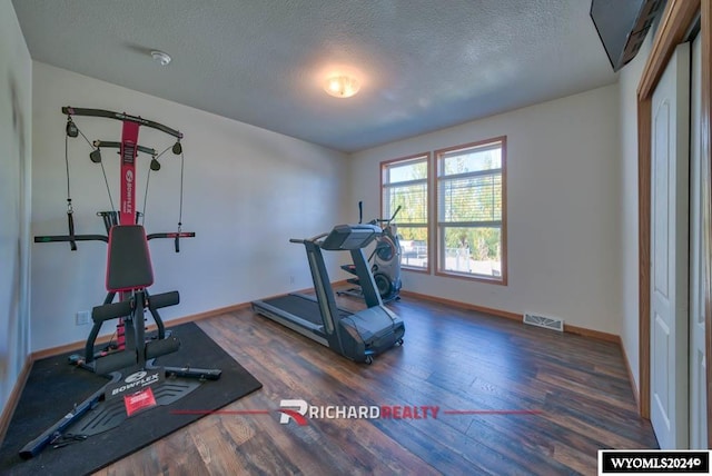 exercise room with a textured ceiling and dark hardwood / wood-style flooring