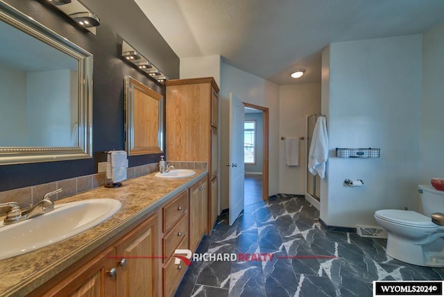 1559 Rd 13, Worland, WY 82401 - full bath with toilet, baseboards, double vanity, marble look tiles, and a shower
