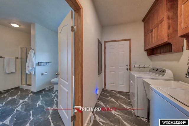 1559 Rd 13, Worland, WY 82401 - laundry area with washer and clothes dryer, cabinet space, dark marble finish flooring, and baseboards