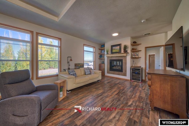 living room with a textured ceiling, dark wood-type flooring, and a fireplace