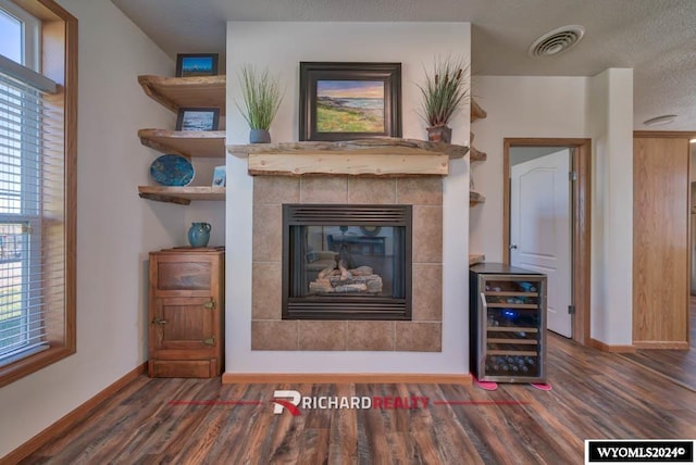 interior space with wine cooler, a textured ceiling, a fireplace, and dark hardwood / wood-style floors