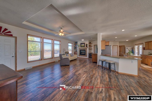 unfurnished living room with dark wood-type flooring, a textured ceiling, and ceiling fan