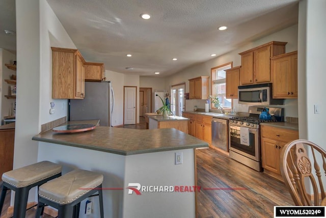 1559 Rd 13, Worland, WY 82401 - kitchen featuring appliances with stainless steel finishes, a center island, a peninsula, dark wood-type flooring, and recessed lighting
