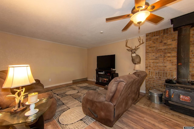 living room with a wood stove, ornamental molding, a fireplace, light hardwood / wood-style floors, and ceiling fan