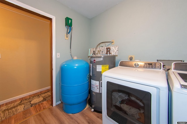 laundry room with water heater, independent washer and dryer, and light wood-type flooring