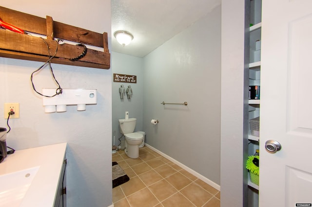 bathroom with toilet, vanity, and tile patterned flooring