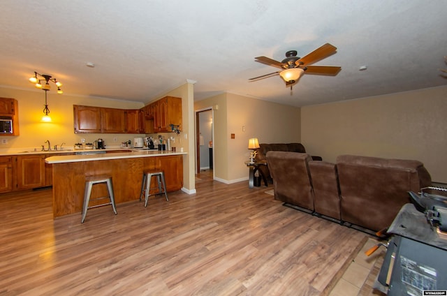 kitchen with light hardwood / wood-style floors, a breakfast bar area, kitchen peninsula, and decorative light fixtures