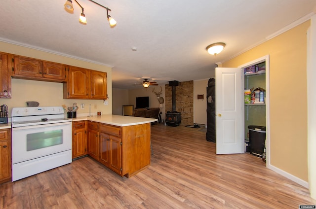 kitchen with a wood stove, white range with electric cooktop, kitchen peninsula, crown molding, and light hardwood / wood-style flooring