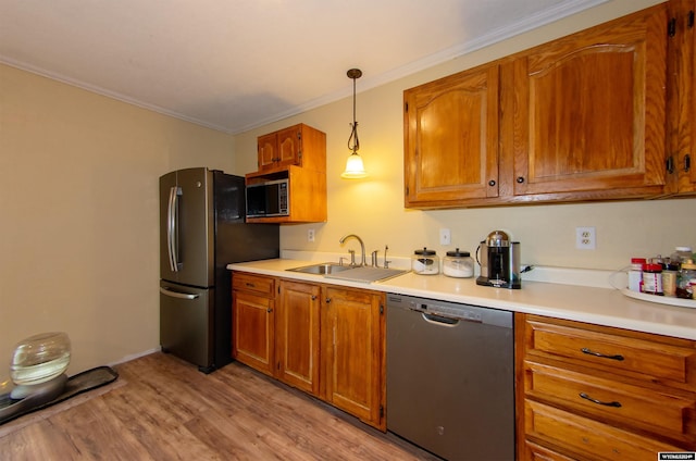 kitchen with sink, crown molding, pendant lighting, appliances with stainless steel finishes, and light hardwood / wood-style floors