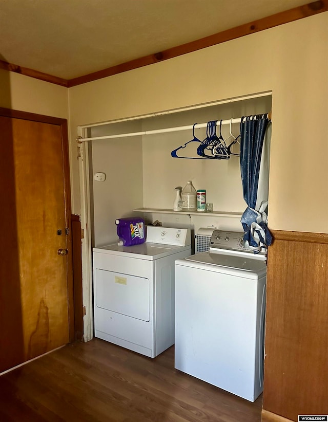 laundry area featuring crown molding, wood walls, washing machine and dryer, and dark hardwood / wood-style flooring