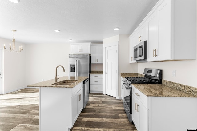 kitchen with hardwood / wood-style flooring, an island with sink, sink, white cabinetry, and appliances with stainless steel finishes