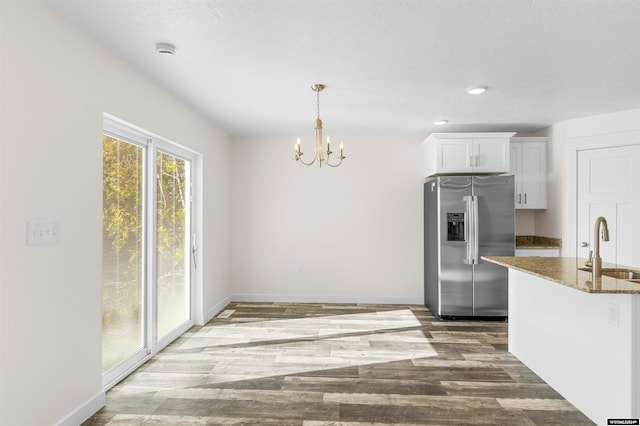 kitchen featuring sink, white cabinets, dark stone countertops, hardwood / wood-style flooring, and stainless steel fridge with ice dispenser