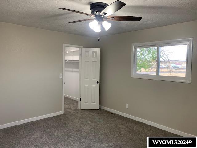 unfurnished bedroom with carpet flooring, ceiling fan, a walk in closet, and a closet