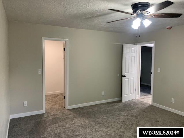 carpeted spare room featuring a textured ceiling and ceiling fan