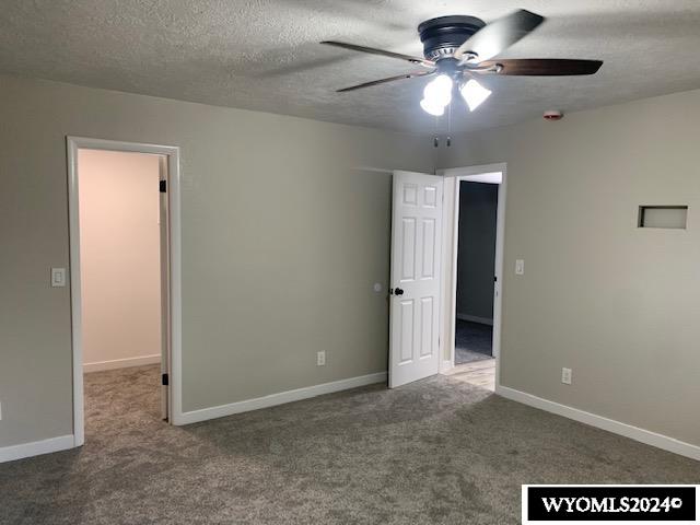 unfurnished bedroom featuring carpet, a textured ceiling, and ceiling fan