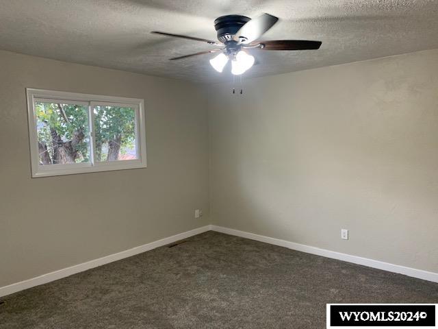 carpeted empty room with ceiling fan and a textured ceiling