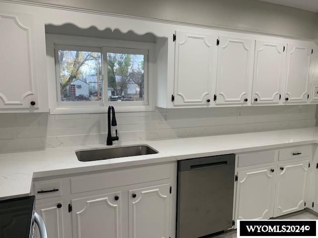 kitchen with white cabinets, sink, tasteful backsplash, light stone counters, and stainless steel appliances