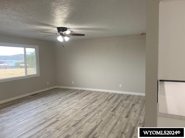 unfurnished room featuring ceiling fan, light hardwood / wood-style floors, and a textured ceiling