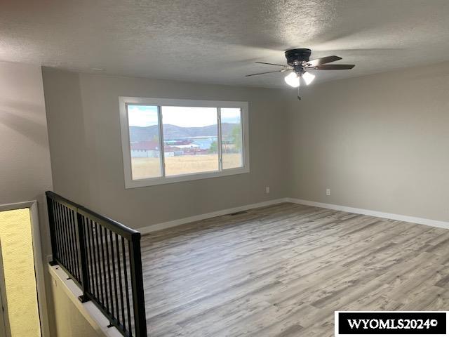 spare room featuring ceiling fan, a mountain view, a textured ceiling, and light wood-type flooring