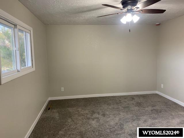 carpeted empty room featuring a textured ceiling and ceiling fan