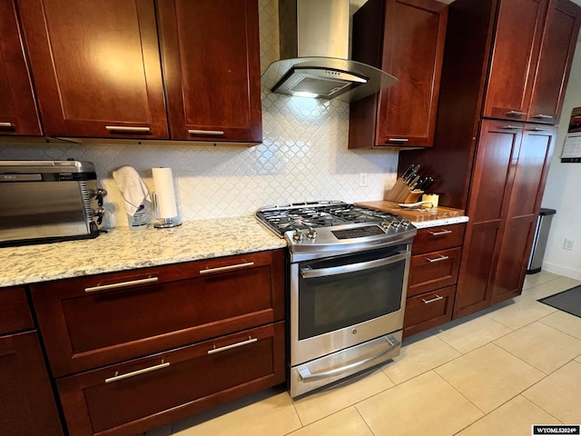 kitchen featuring decorative backsplash, light stone countertops, light tile patterned flooring, stainless steel range with gas stovetop, and wall chimney exhaust hood