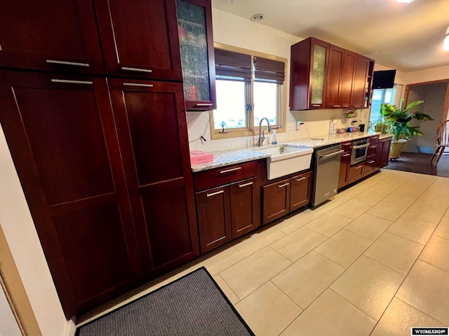 kitchen featuring stainless steel dishwasher, sink, light stone counters, and light tile patterned floors