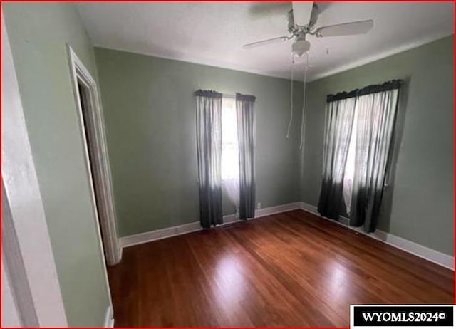 spare room with dark wood-type flooring and ceiling fan