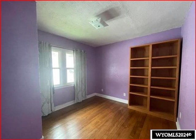 unfurnished room with a textured ceiling and wood-type flooring