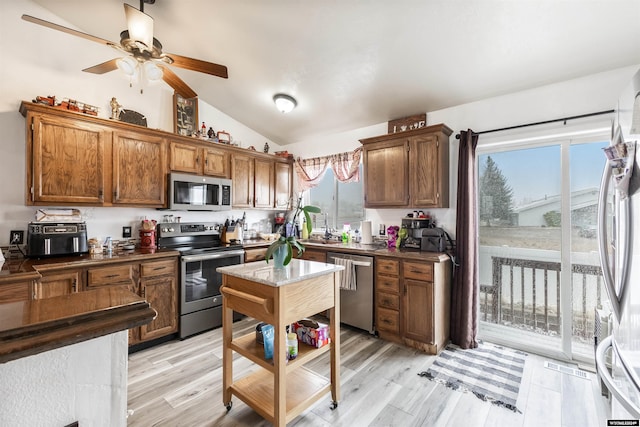 kitchen featuring light hardwood / wood-style floors, stainless steel appliances, lofted ceiling, and plenty of natural light