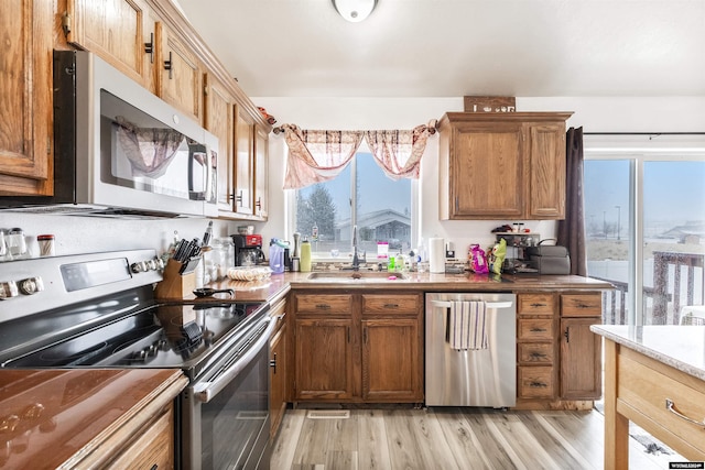 kitchen with stainless steel appliances, sink, and light wood-type flooring