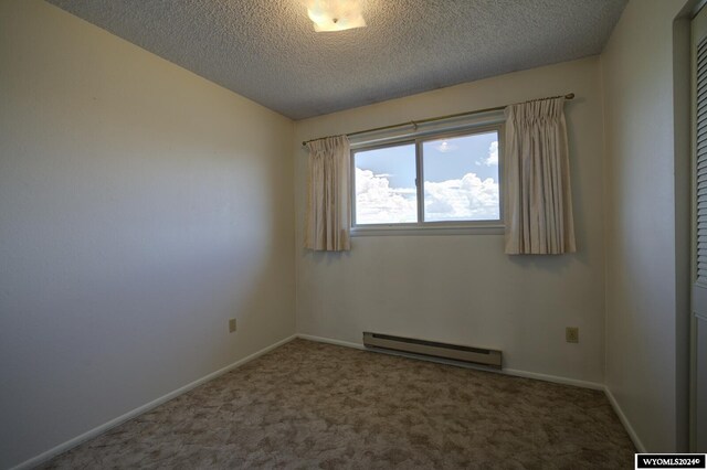 empty room featuring a textured ceiling, a baseboard heating unit, and carpet floors