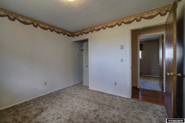 carpeted empty room featuring a textured ceiling