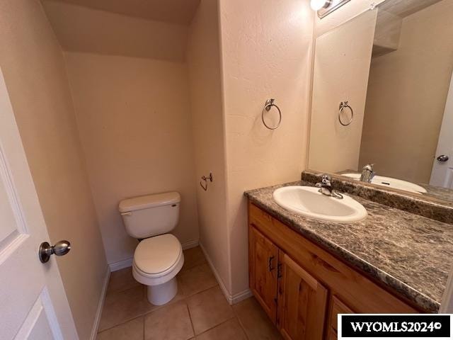 bathroom with toilet, vanity, and tile patterned floors