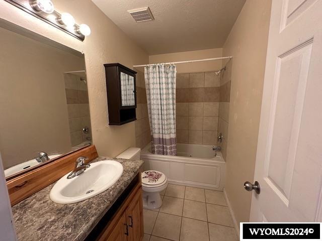 full bathroom featuring shower / bath combination with curtain, a textured ceiling, toilet, vanity, and tile patterned flooring