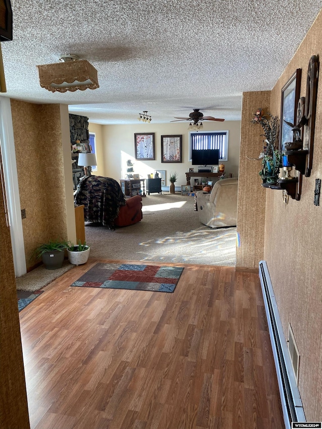 corridor featuring a baseboard heating unit, a textured ceiling, and hardwood / wood-style flooring