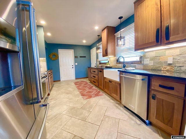 kitchen with hanging light fixtures, backsplash, sink, light tile patterned floors, and appliances with stainless steel finishes