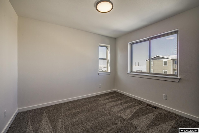 unfurnished room featuring dark colored carpet