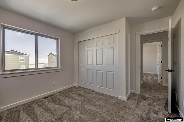 unfurnished bedroom featuring dark colored carpet and a closet