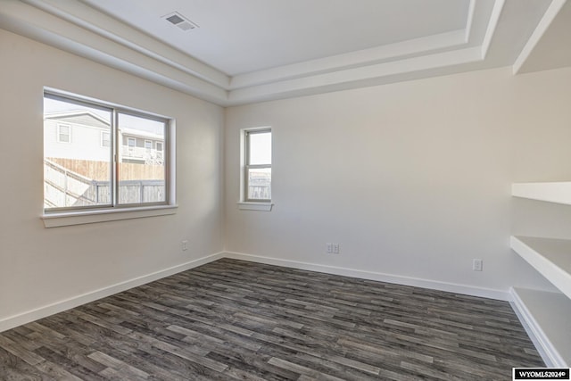 empty room featuring dark wood-type flooring and a tray ceiling