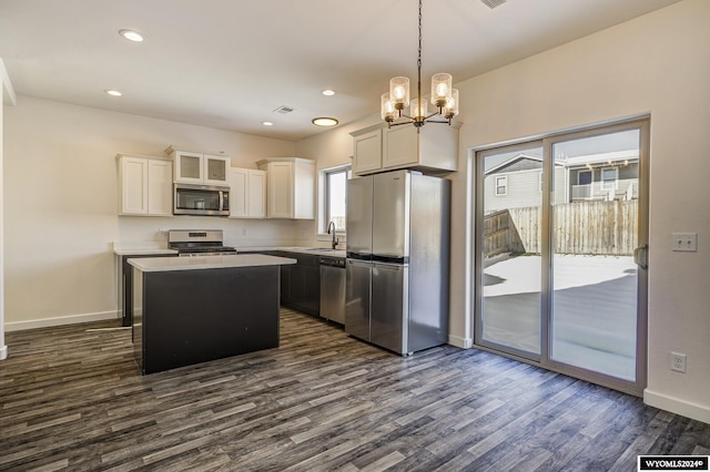 kitchen with stainless steel appliances, white cabinetry, decorative light fixtures, dark wood-type flooring, and a center island